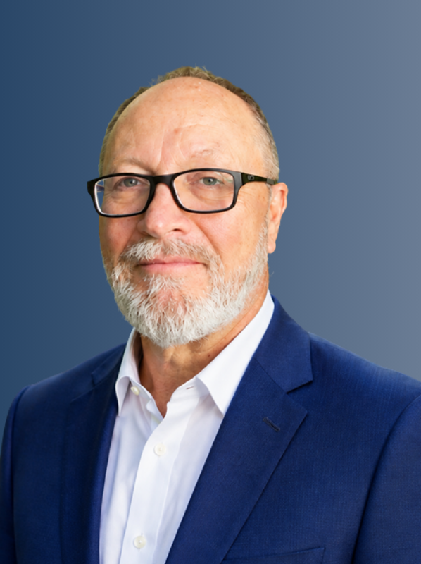 Professional headshot of Roger Baldridge, a strategy and management consultant, wearing glasses and a blue suit