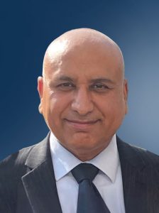 Dan Maxwell headshot in a dark suit and tie against a blue background, highlighting trade promotion and pricing leadership with years of experience.